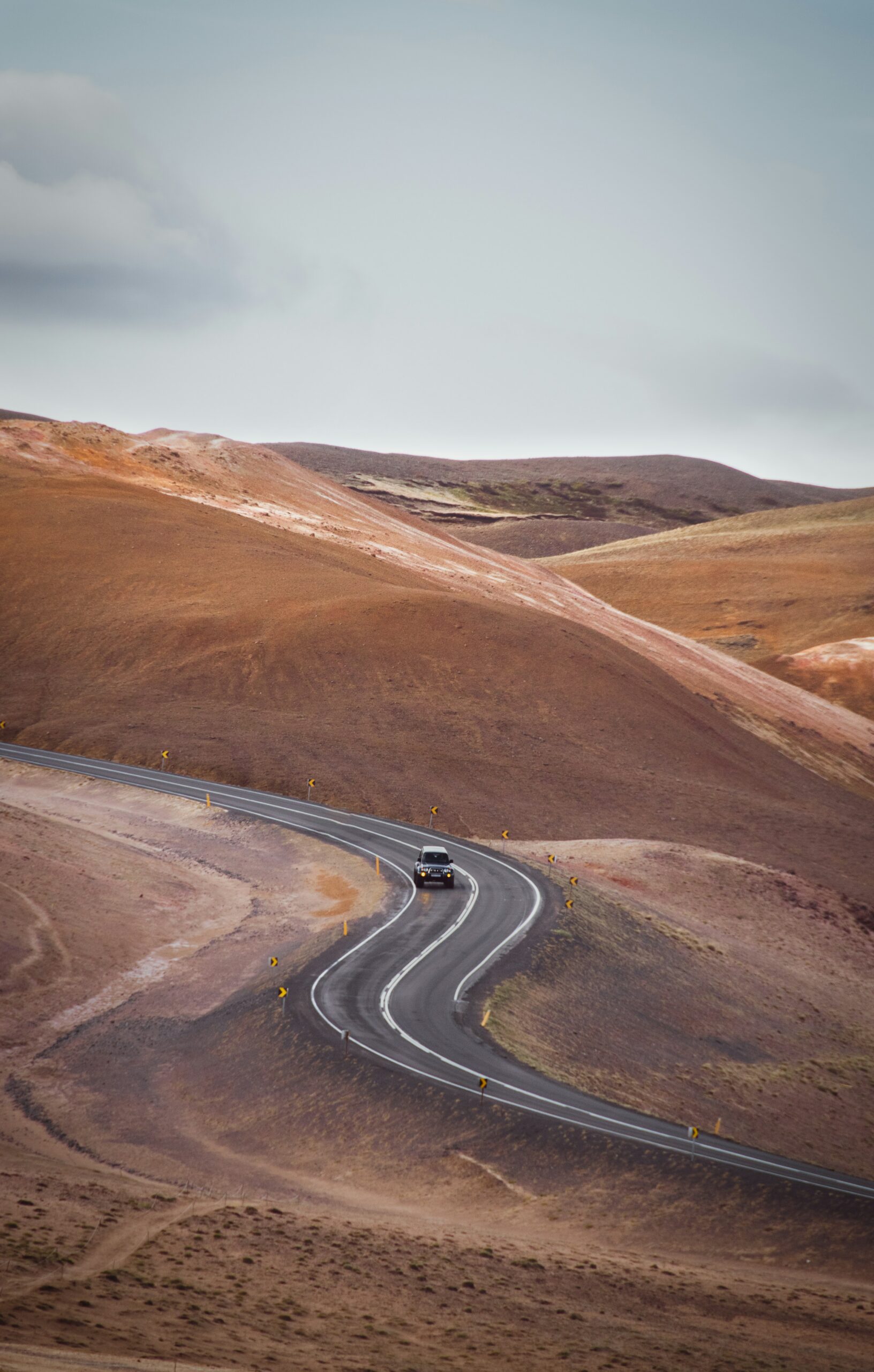 Car driving on winding road through the red hills of Myvatn in North Iceland